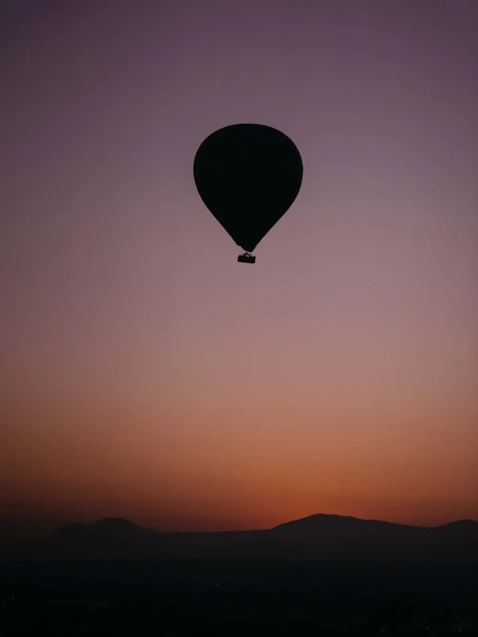 A lone hot air balloon in the dawn haze over the Teotihuacan valley