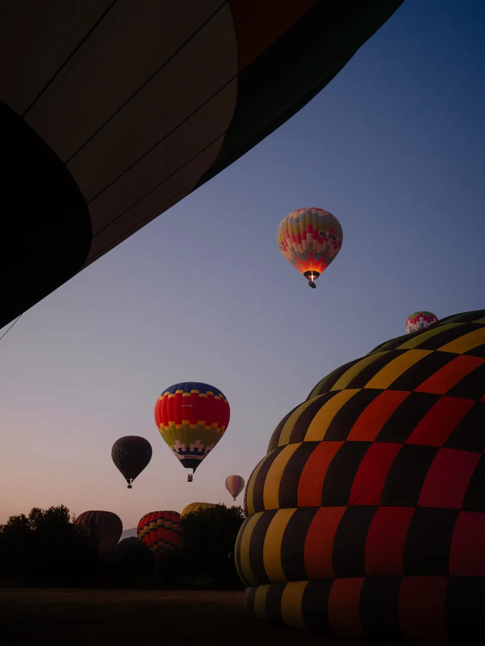 A hot air balloon being inflated on the launch field near Teotihuacan before sunrise, with the crew working in the dark