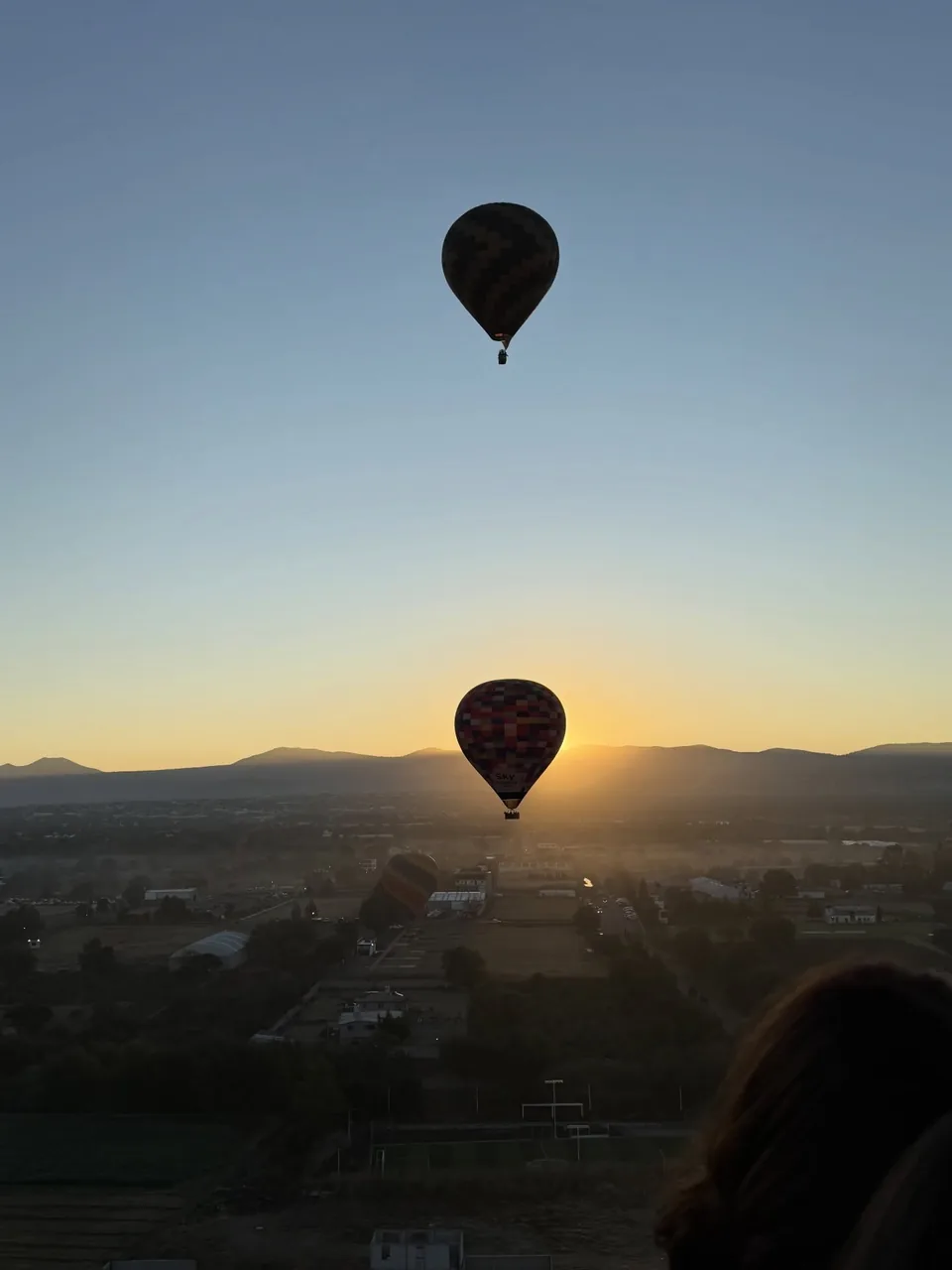 A hot air balloon in silhouette as the sun rises over the hills near Teotihuacan