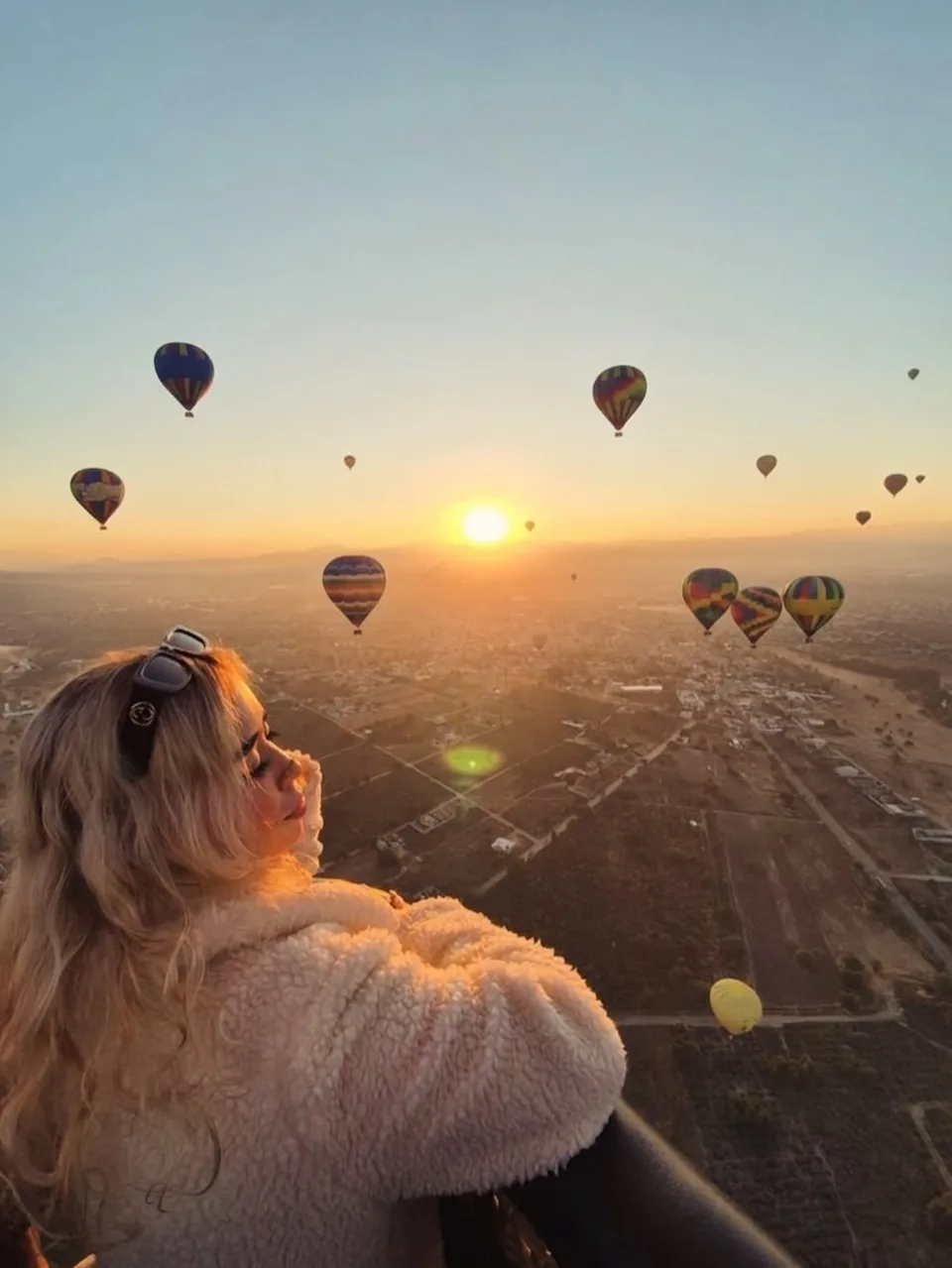 A passenger watching the sun come up over the Teotihuacan valley from inside the balloon basket