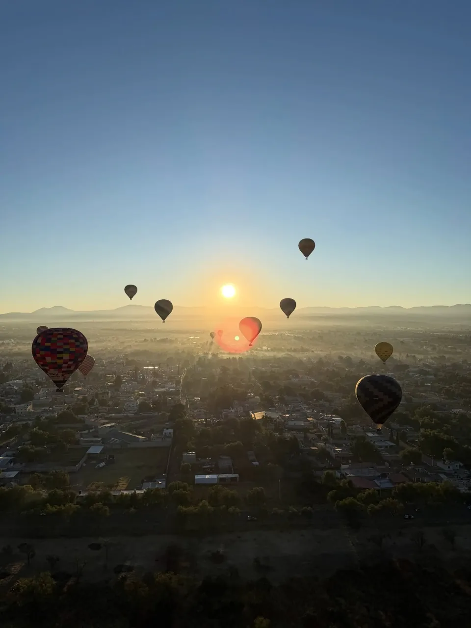 The sun breaking the horizon over the Teotihuacan valley seen from a hot air balloon already in the air