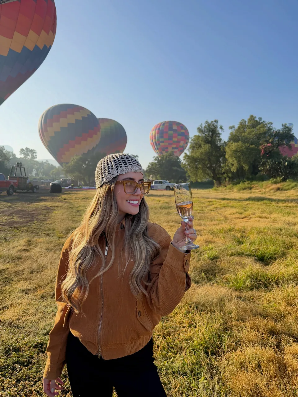 A traveler raises a glass beside the balloons after landing in the fields at Teotihuacan