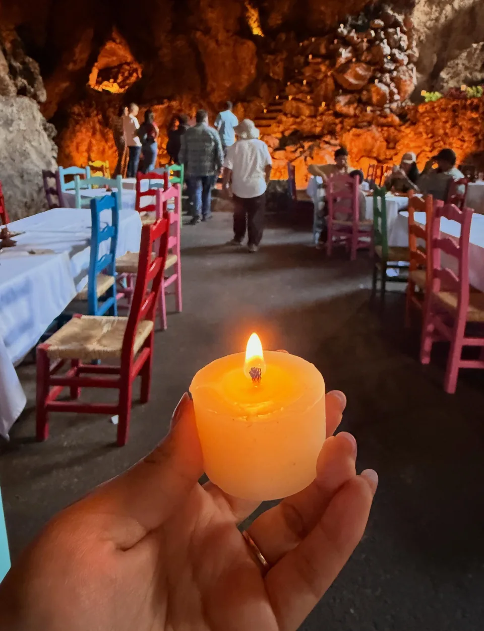 A lit candle held in the hand inside La Gruta Teotihuacan
