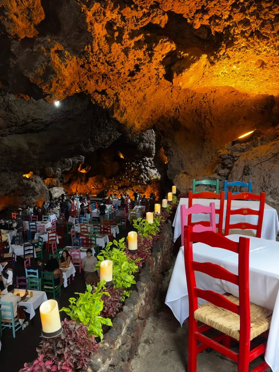 Candles on a laid table beside red chairs at La Gruta Teotihuacan